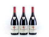 three bottles of red wine sitting next to each other on a white surface