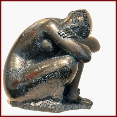 une statue représentant un homme assis par terre, la tête entre les mains