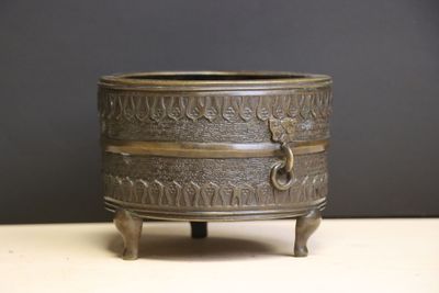 a small bronze pot on a stand on a table