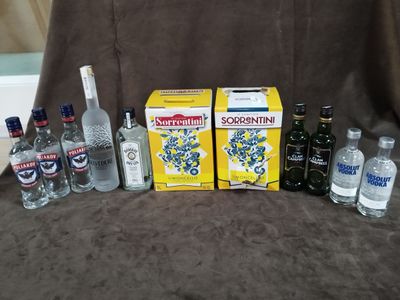 plusieurs bouteilles d'alcool et une caisse de vodka posées sur un canapé