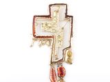 a gold cross with a red and gold bead hanging from it