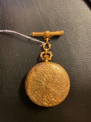 gros plan d'une montre de poche en or sur une surface noire