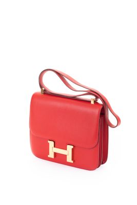 un sac à main en cuir rouge avec des finitions dorées sur fond blanc