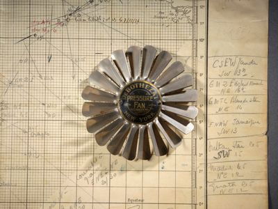 une fleur en métal posée sur un morceau de papier, lui-même posé sur un autre morceau de papier