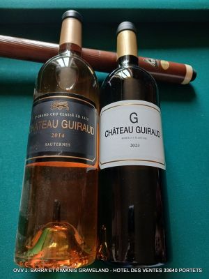 deux bouteilles de vin et un cigare posés sur une table de billard