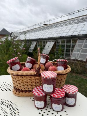 un panier de confitures posé sur une table devant une serre