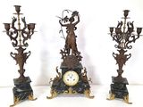 three different types of candlesticks and a clock on a table