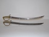 pair of two swords on a white surface with a pair of scissors in the foreground