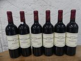 six bouteilles de vin rouge sont alignées sur une table en bois