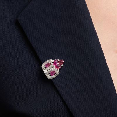 a close up of a person wearing a suit with a pink and white broocher