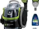 a green and black vacuum cleaner and a bottle of cleaner