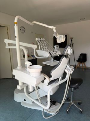 a dentist ' s chair in the middle of a room with a clock on the wall