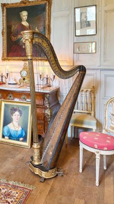 une grande harpe au milieu d'une pièce où est accroché un tableau au mur