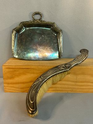un porte-monnaie en argent et une brosse posés sur une étagère en bois