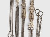 three silver necklaces and a pair of scissors on a white surface