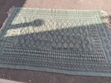 un tapis bleu posé par terre, sur lequel se dessine une ombre