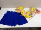 a white table topped with two blue shorts and a yellow top