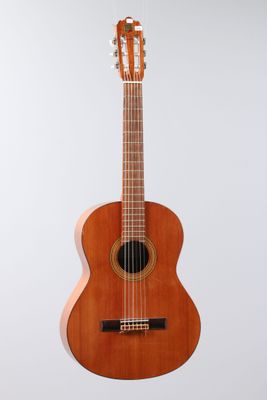 a small wooden guitar hanging from a white wall