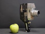 an apple next to an old movie camera on a table
