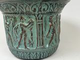 a green vase with a design on it on a white surface
