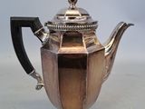 an antique silver teapot with a black handle sitting on a table