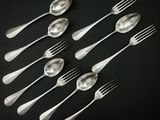 six cuillères en argent et six cuillères en argent posées sur un fond noir