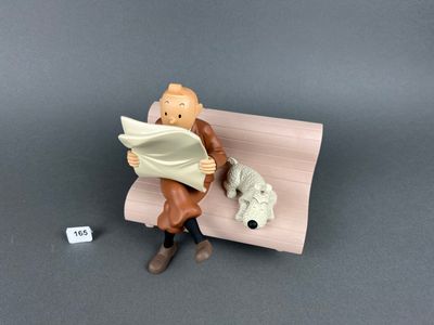 une figurine représentant un homme assis sur un banc avec un chien