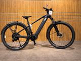 une photo d'un vélo électrique noir garé devant un mur en bois