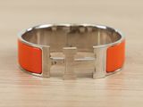 an orange bracelet with a silver buckle on top of a wooden table
