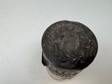 a silver vase with a black lid sitting on a white surface
