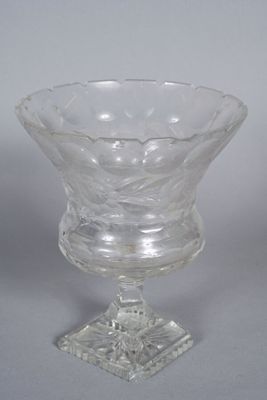 a glass bowl on a stand on a white surface