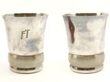 two silver cups sitting next to each other on a white surface