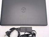 dell laptop with power cord and charger sitting on a white surface
