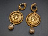 two gold earrings with pearls and a coin on them