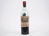 une vieille bouteille de vin posée sur une surface blanche