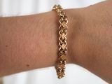 a woman ' s arm with a gold bracelet on it