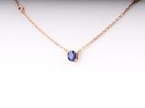 a gold necklace with a blue stone on a white background