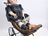 a small doll sitting in a wicker doll carriage