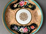 a plate with a flower design on it next to a vase