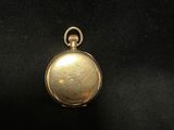 a close up of a gold pocket watch on a black surface