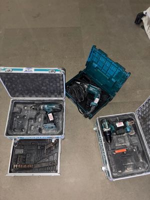 trois valises ouvertes posées par terre, contenant des outils