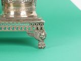 a silver vase sitting on top of a green table