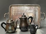 three silver teapots and a silver tray on a table