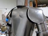 un homme en armure, debout dans une pièce