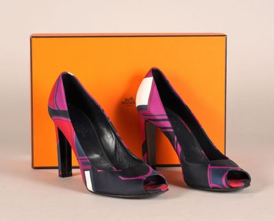 une paire d'escarpins noirs et roses, avec une boîte en arrière-plan