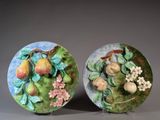 two decorative plates with fruit and flowers on them on a table