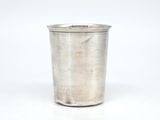 une vieille coupe en argent munie d'une anse, posée sur une surface blanche
