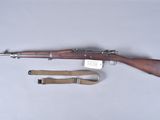 un vieux fusil avec un canon en bois et une bretelle, posé sur une table