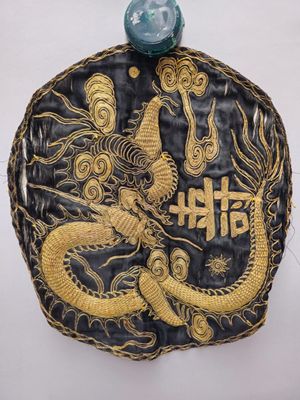 une image représentant une pièce noire et dorée sur laquelle figure un dragon