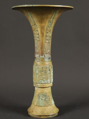 an old bronze vase sitting on top of a black table